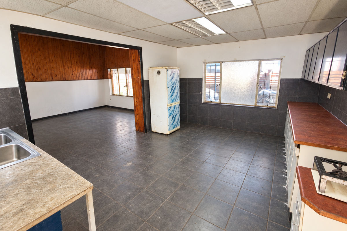 Spacious kitchen area featuring dark tiled flooring, built-in cabinetry with laminate countertops, and a drop ceiling, offering significant potential for modernization.