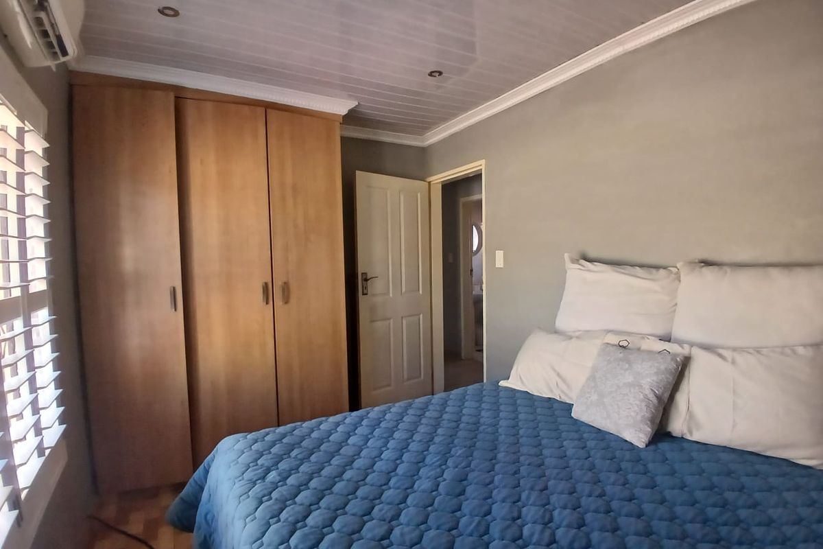 A bedroom featuring a built-in wardrobe, air conditioning unit, and a timber-look ceiling with recessed lighting.