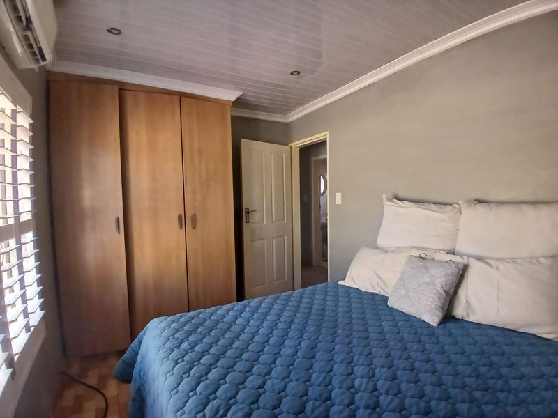 A bedroom featuring a built-in wardrobe, air conditioning unit, and a timber-look ceiling with recessed lighting.
