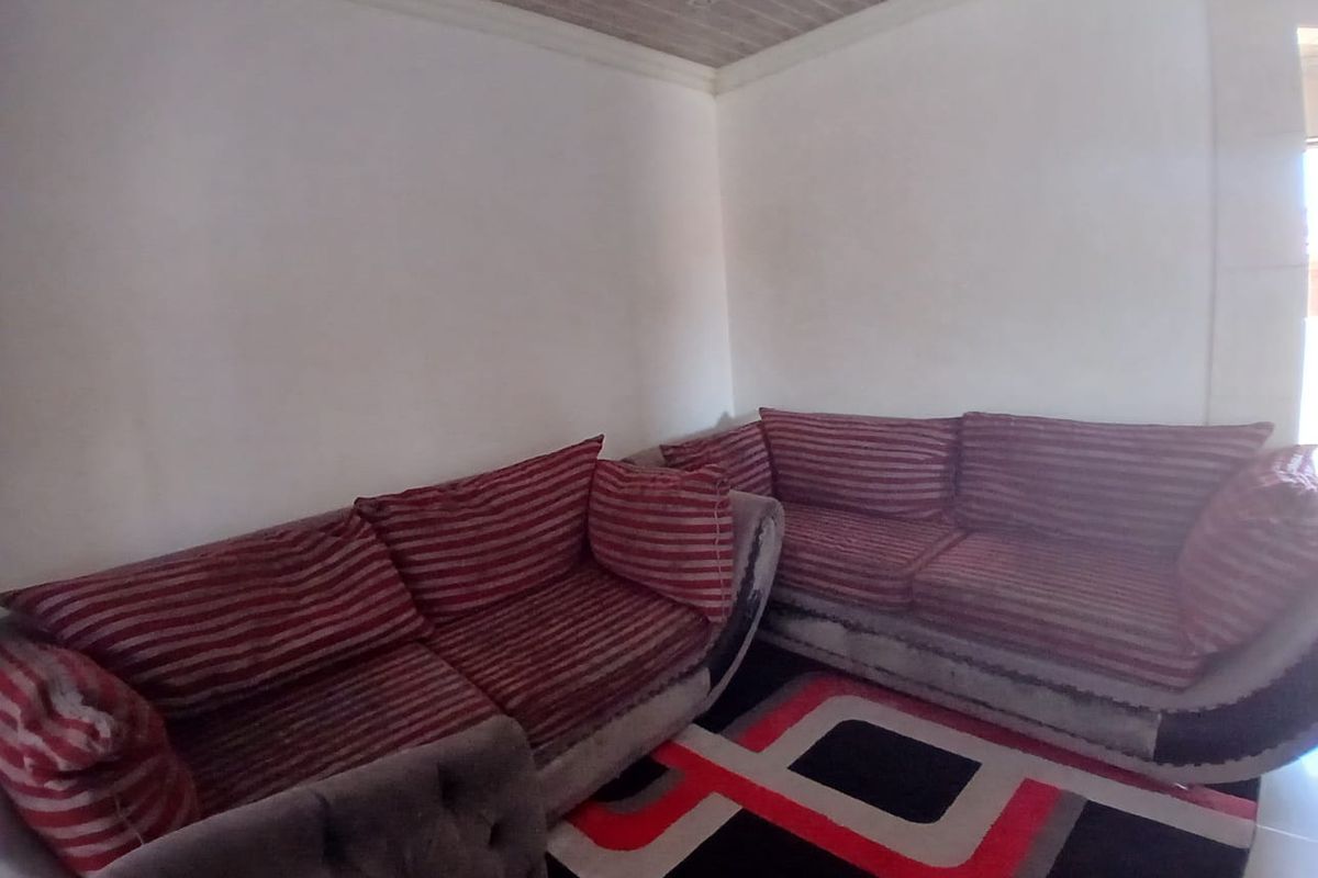 A living room area featuring white walls and a wood-paneled ceiling.