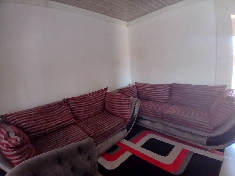 A living room area featuring white walls and a wood-paneled ceiling.