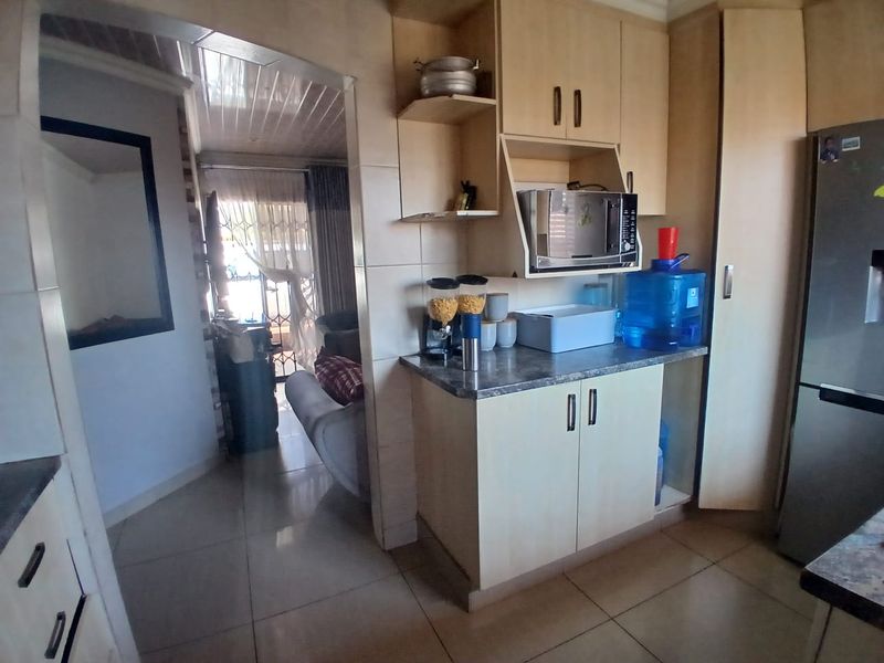 A compact kitchen area featuring built-in cabinetry, laminate countertops, and tiled flooring, providing functional storage and preparation space.