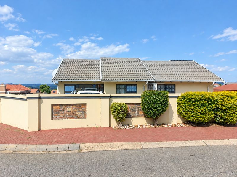 Front view of a single-story residential property featuring a tiled roof, perimeter boundary wall with stone accents, and security bars on windows.