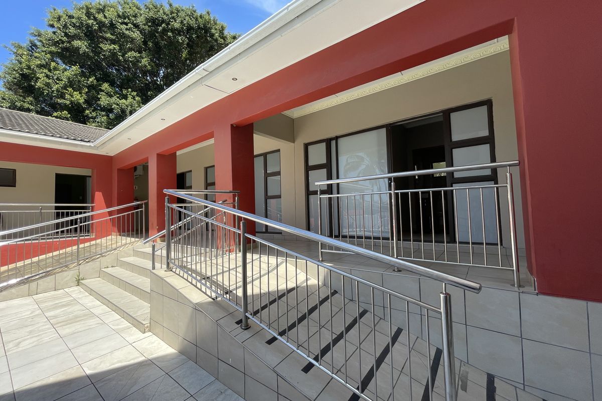 A well-maintained covered patio area featuring a tiled ramp and stairs with stainless steel handrails, providing accessible entry to the guest house.