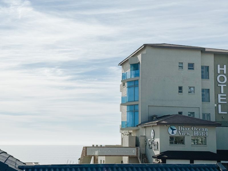 Exterior view of a multi-story hotel building featuring balconies with glass balustrades and ocean views.