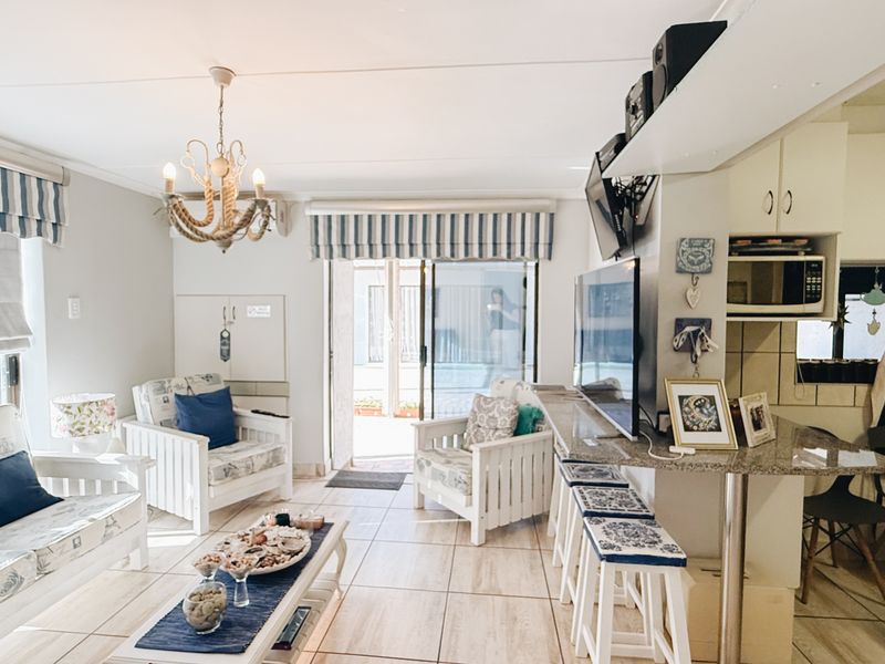 Open-plan living and kitchen area featuring tiled flooring, granite countertops, and direct access to a patio through sliding glass doors.