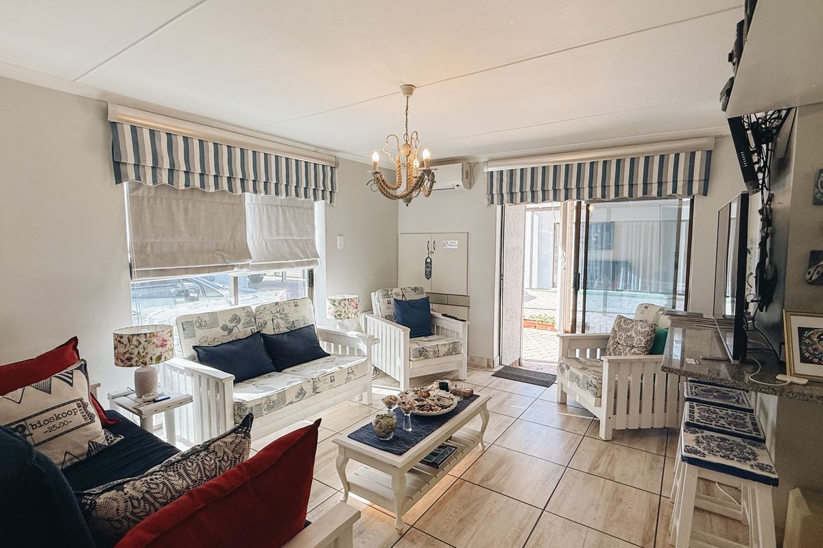 A bright living room featuring tiled flooring, a built-in breakfast bar, and a sliding glass door providing access to the outdoor area.