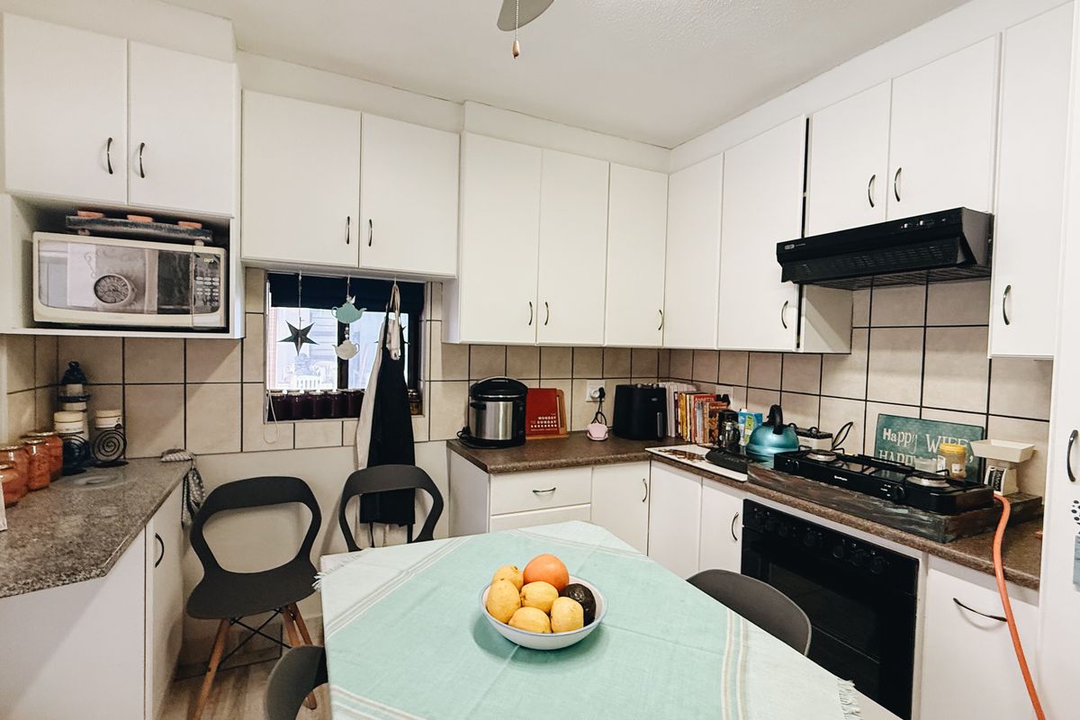 A functional kitchen featuring white cabinetry, tiled backsplash, built-in oven, gas hob, and extractor fan with ample storage space.