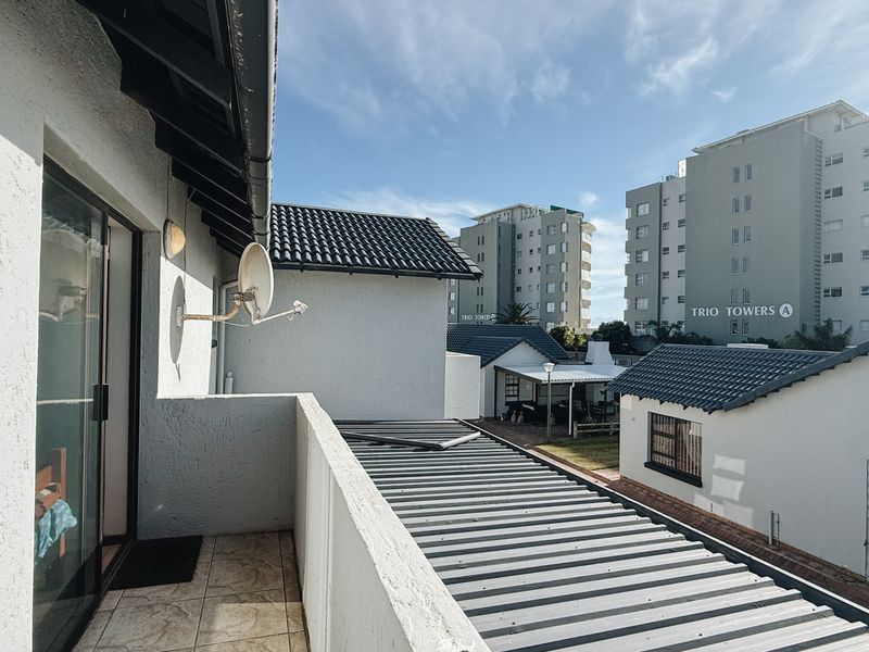 An elevated balcony with tiled flooring, offering views of the surrounding townhouse complex and nearby apartment buildings.