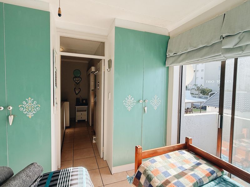 Bedroom featuring built-in cupboards, tiled flooring, and a sliding glass door providing access to an outdoor balcony area.