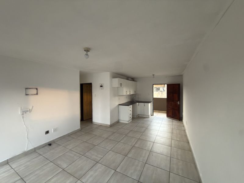 An open-plan living and kitchen area featuring tiled flooring, built-in cabinetry, and direct access to an outdoor balcony.