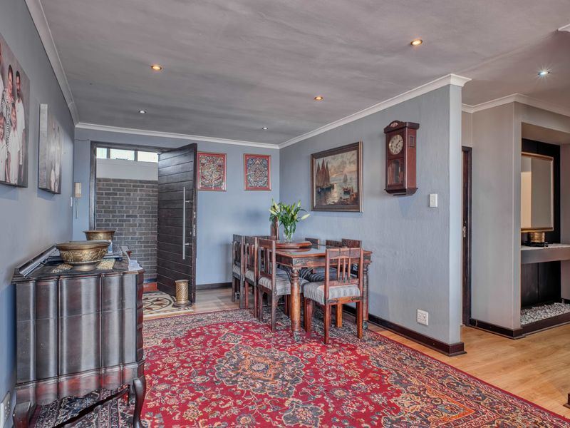 A well-maintained dining area featuring timber flooring, recessed lighting, and a coved ceiling, providing a warm and inviting space for formal meals.