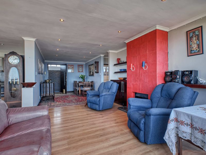 Spacious open-plan living and dining area featuring laminate flooring, recessed lighting, and a prominent red tiled fireplace feature wall.