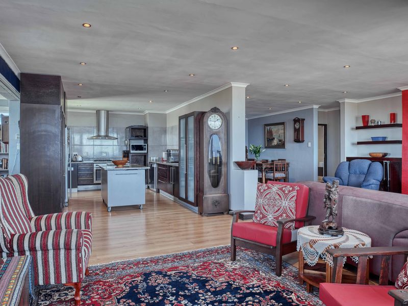 Spacious open-plan living area featuring a modern kitchen with island, laminate flooring, recessed lighting, and a fireplace, creating a versatile and functional living space.