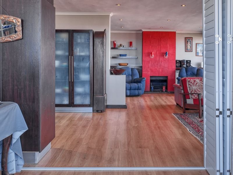 Spacious living area featuring laminate flooring, recessed lighting, and a prominent red tiled fireplace surround with integrated shelving.