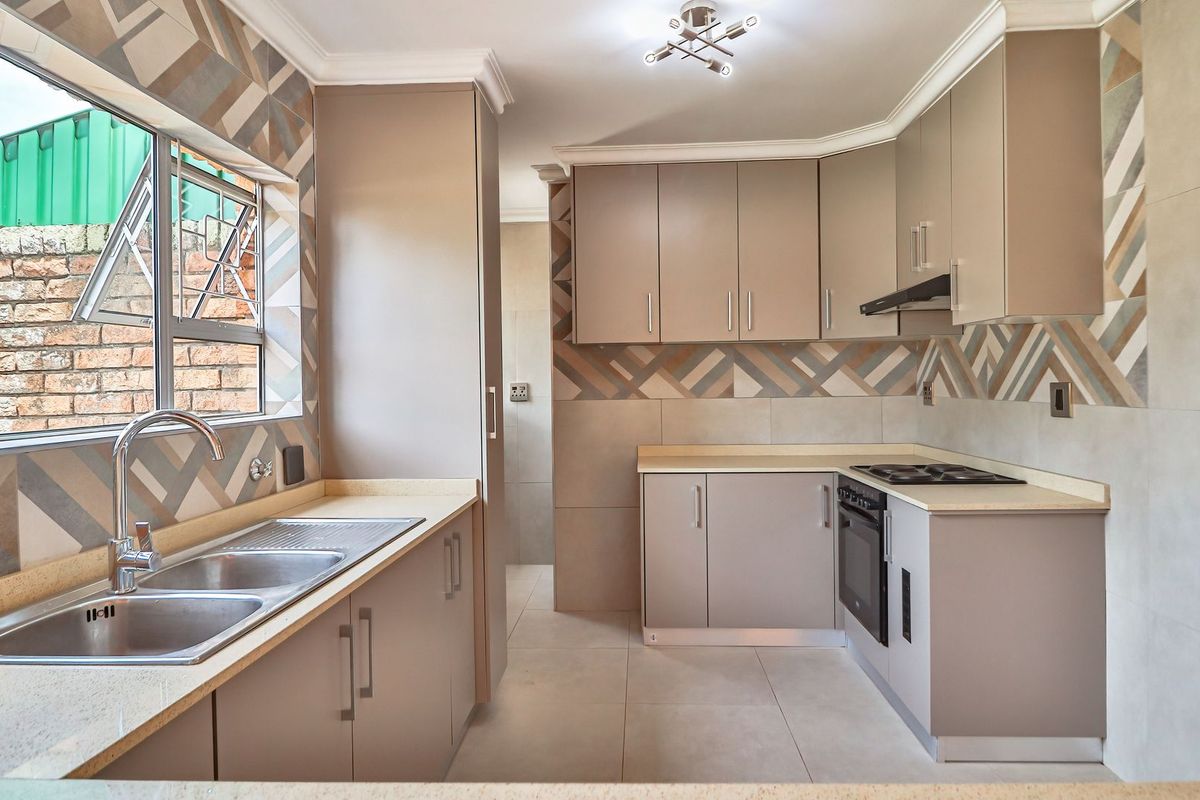 Modern kitchen featuring neutral cabinetry, stone countertops, tiled splashbacks, and integrated appliances including an oven, hob, and extractor fan.