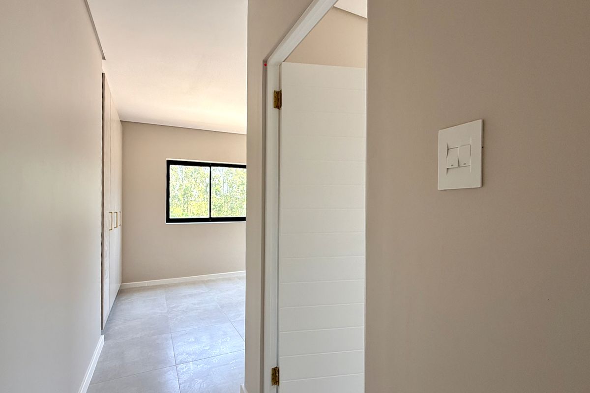 A bright, empty bedroom featuring neutral tiled flooring, built-in cupboards, and a modern window, offering a clean and versatile space ready for personalization.