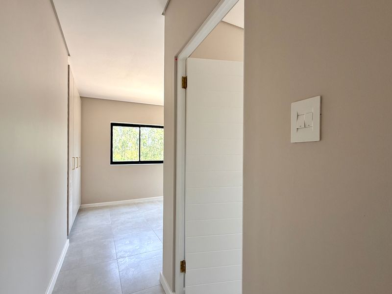 A bright, empty bedroom featuring neutral tiled flooring, built-in cupboards, and a modern window, offering a clean and versatile space ready for personalization.