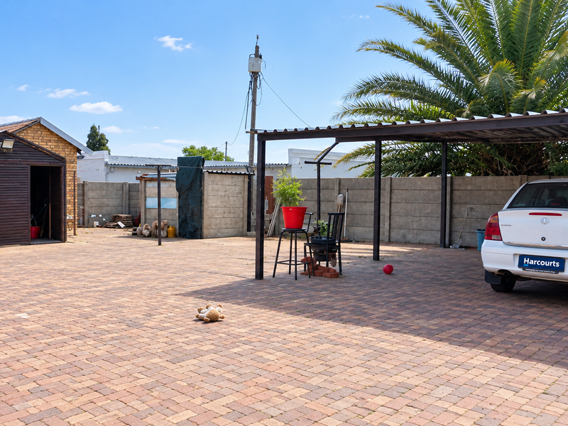 Spacious paved rear yard featuring a covered carport, storage shed, and secure precast concrete boundary walls.