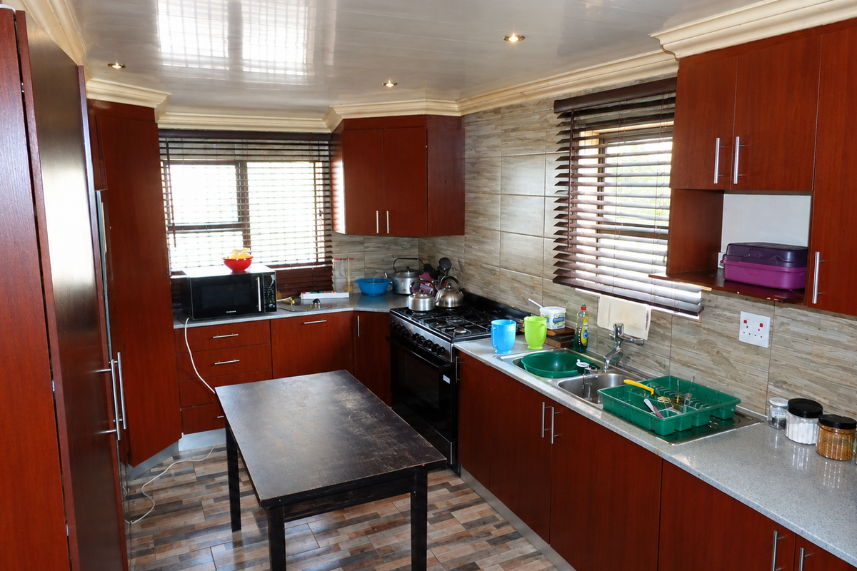 A functional kitchen featuring dark wood cabinetry, a gas stove with oven, tiled backsplash, and ample counter space with a double sink.