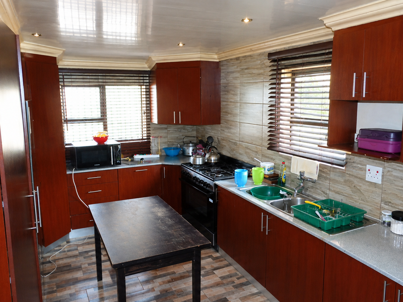 A functional kitchen featuring dark wood cabinetry, a gas stove with oven, tiled backsplash, and ample counter space with a double sink.