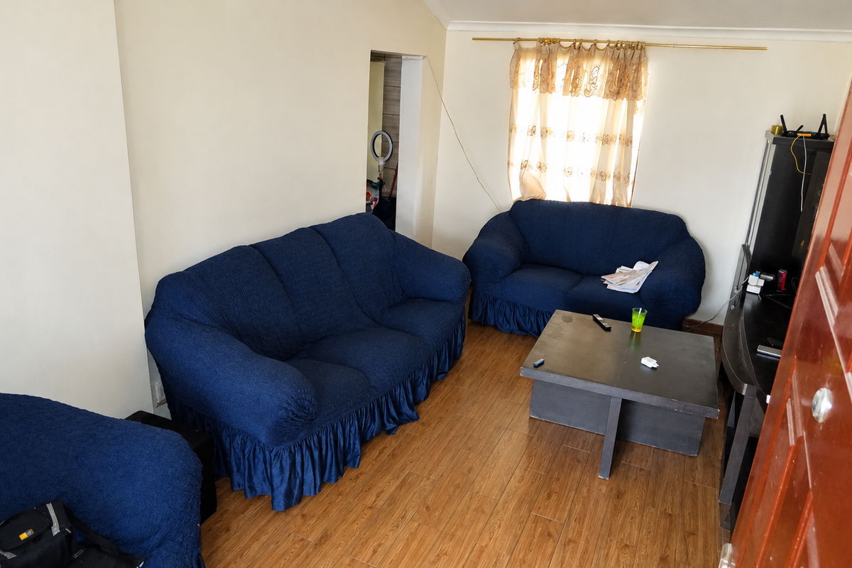 A living room featuring laminate flooring and coved ceiling details, providing a functional space for relaxation.