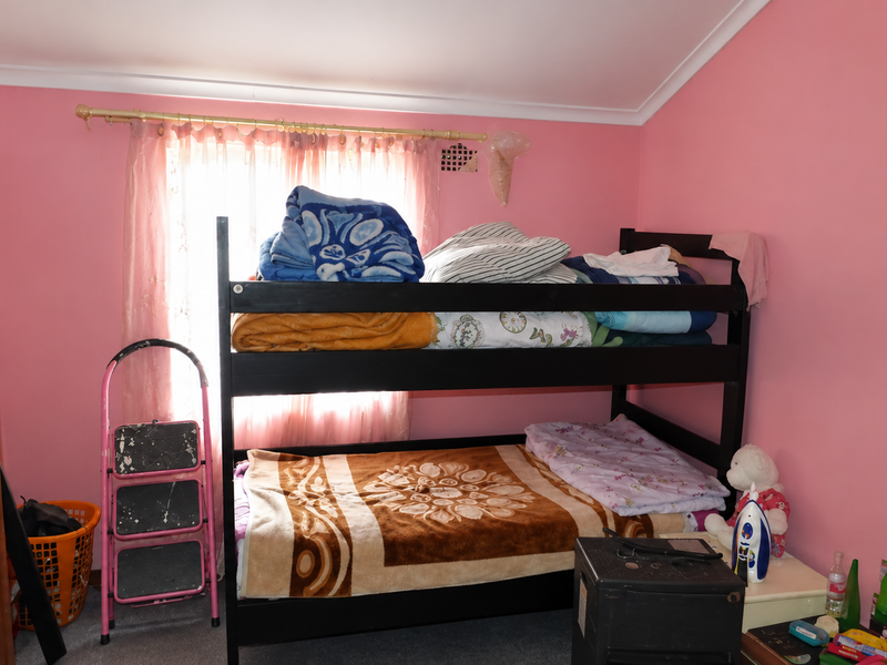 A bedroom featuring pink walls, a window with curtains, and a cove cornice. The room requires cosmetic updates to improve its overall condition.