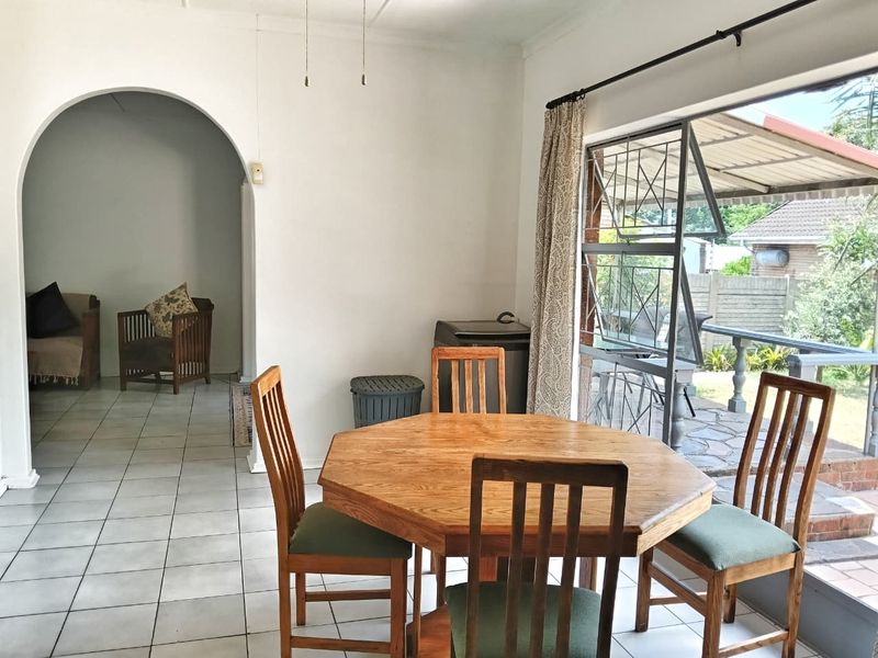 Dining area featuring tiled flooring, an arched entryway, and a large sliding glass door providing access to the outdoor patio area.