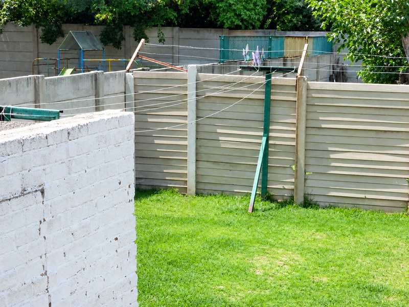 A private backyard area featuring a lawn, precast concrete boundary walls, and a fixed washing line.