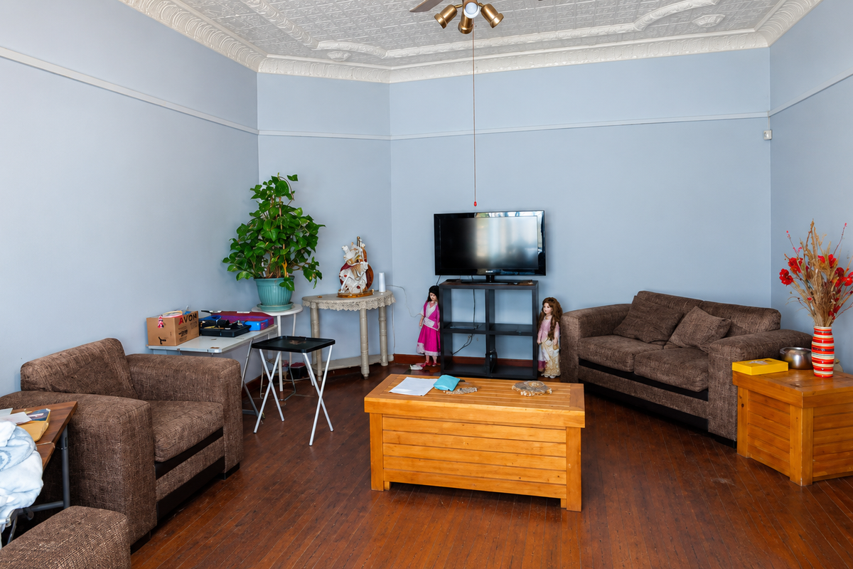 A living room featuring original pressed metal ceilings, hardwood flooring, and a picture rail, offering a classic architectural foundation for modern updates.