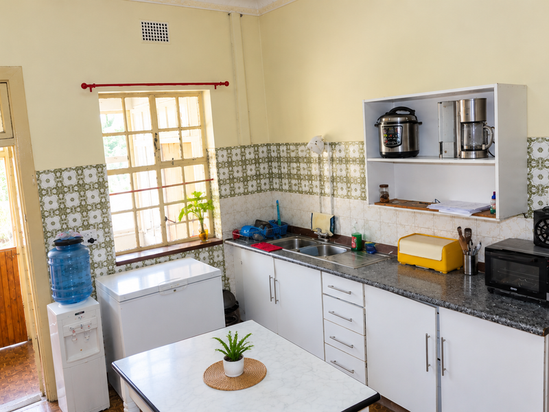 A functional kitchen featuring white cabinetry, laminate countertops, a double sink, and decorative tiled backsplash with direct access to an exterior door.