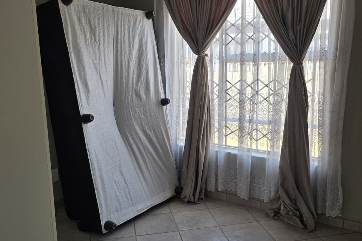 A bedroom featuring tiled flooring, security gate on the window, and neutral wall finishes.