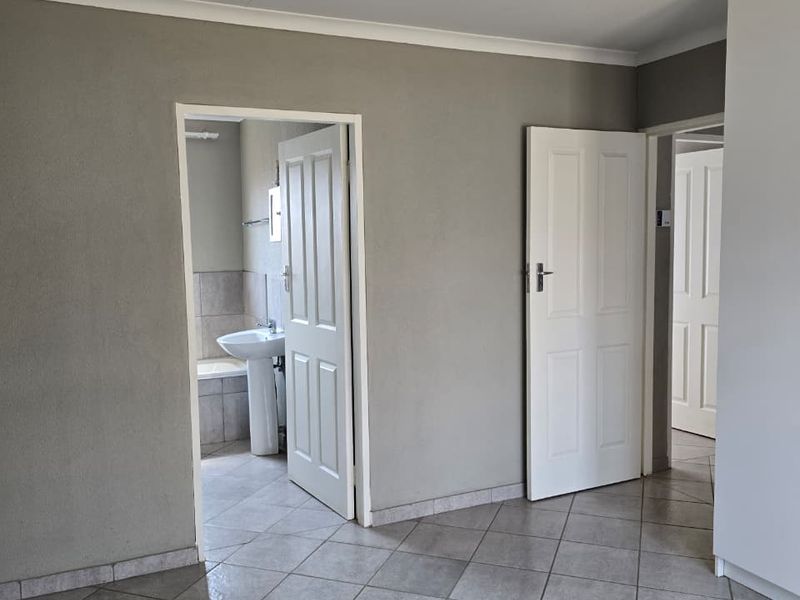 An empty bedroom featuring tiled flooring, built-in storage, and direct access to an en-suite bathroom.