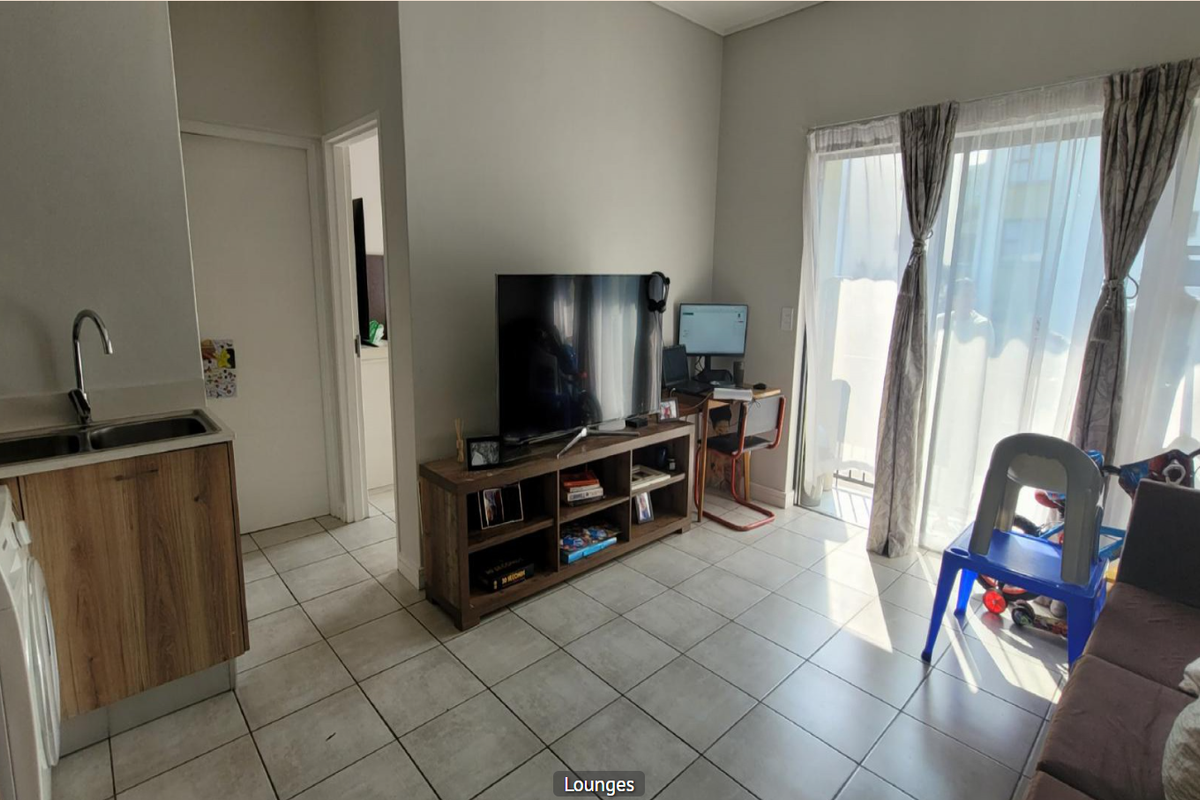 Open plan living area featuring tiled flooring, a compact kitchen with built-in cabinetry, and a sliding glass door providing access to the exterior.