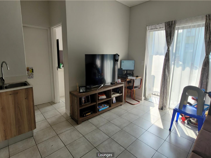 Open plan living area featuring tiled flooring, a compact kitchen with built-in cabinetry, and a sliding glass door providing access to the exterior.