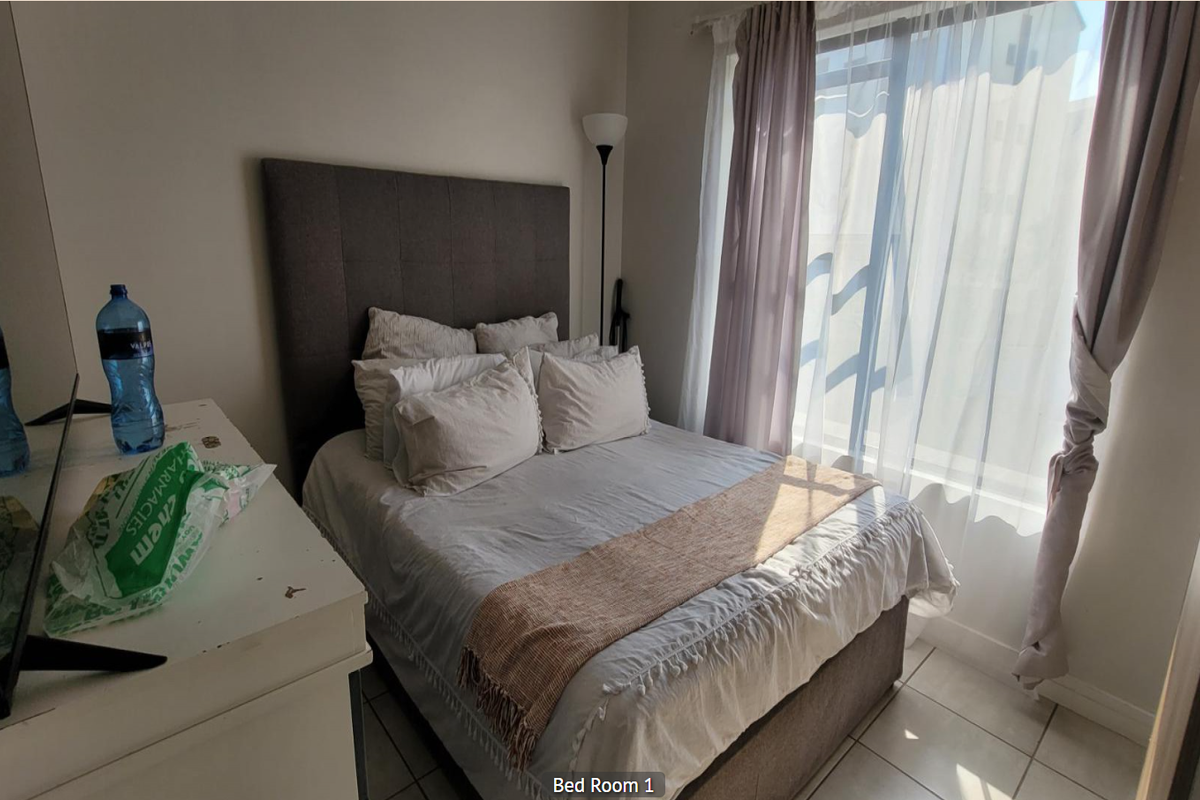 A bedroom featuring tiled flooring and a sliding door providing natural light.