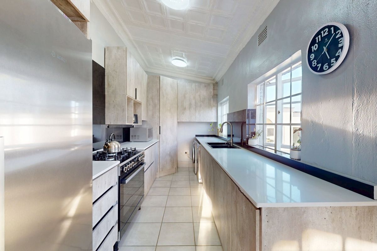 Modern kitchen featuring light wood-grain cabinetry, stone countertops, a gas hob, and a double sink, complemented by classic pressed metal ceilings.