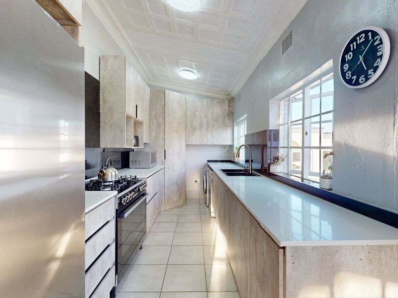 Modern kitchen featuring light wood-grain cabinetry, stone countertops, a gas hob, and a double sink, complemented by classic pressed metal ceilings.