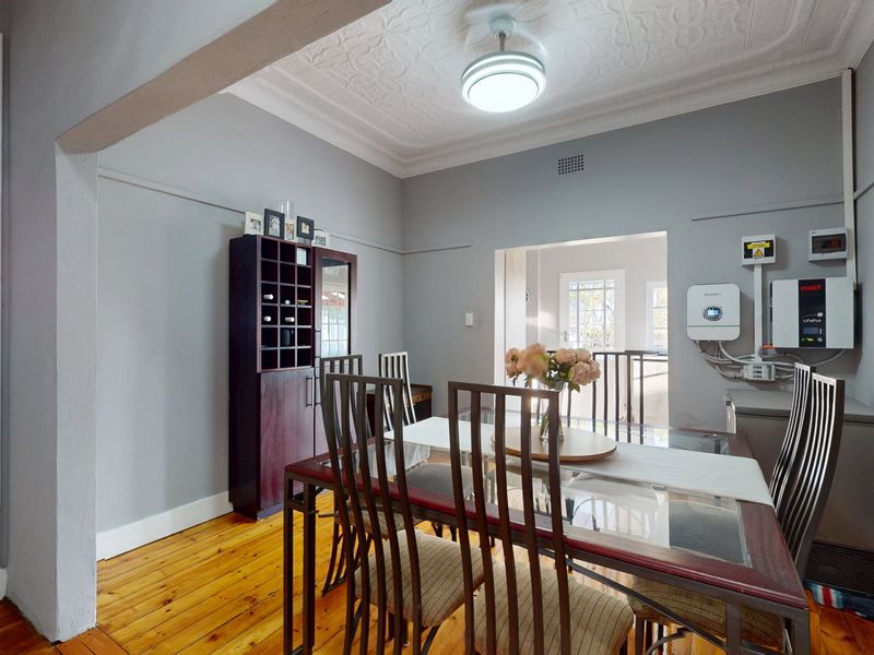 Dining room featuring original pressed metal ceilings, polished timber flooring, and wall-mounted solar power infrastructure.