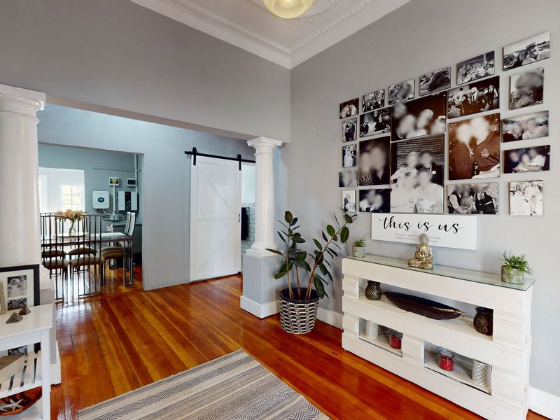 Spacious living area featuring polished hardwood floors, decorative ceiling cornices, and elegant classical columns leading into an adjacent dining space.