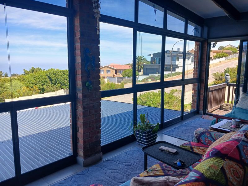 Enclosed patio area featuring exposed brick pillars, large glass windows providing expansive views, and tiled flooring, creating a bright and airy living space.