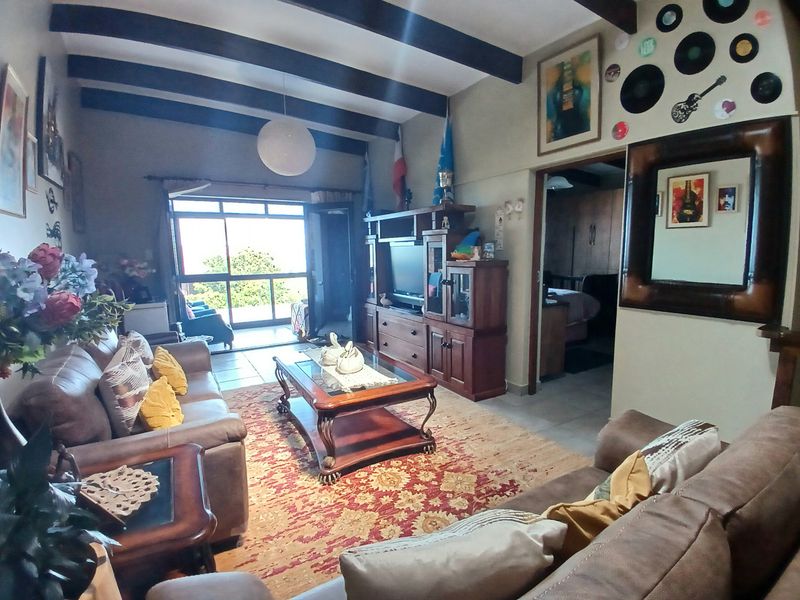 Spacious living room featuring exposed timber ceiling beams, tiled flooring, and a sliding glass door providing access to the outdoor patio area.