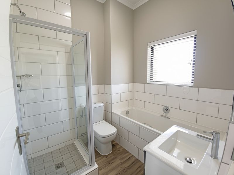Modern bathroom featuring a glass shower enclosure, built-in bathtub, vanity basin, and clean subway tile finishes.
