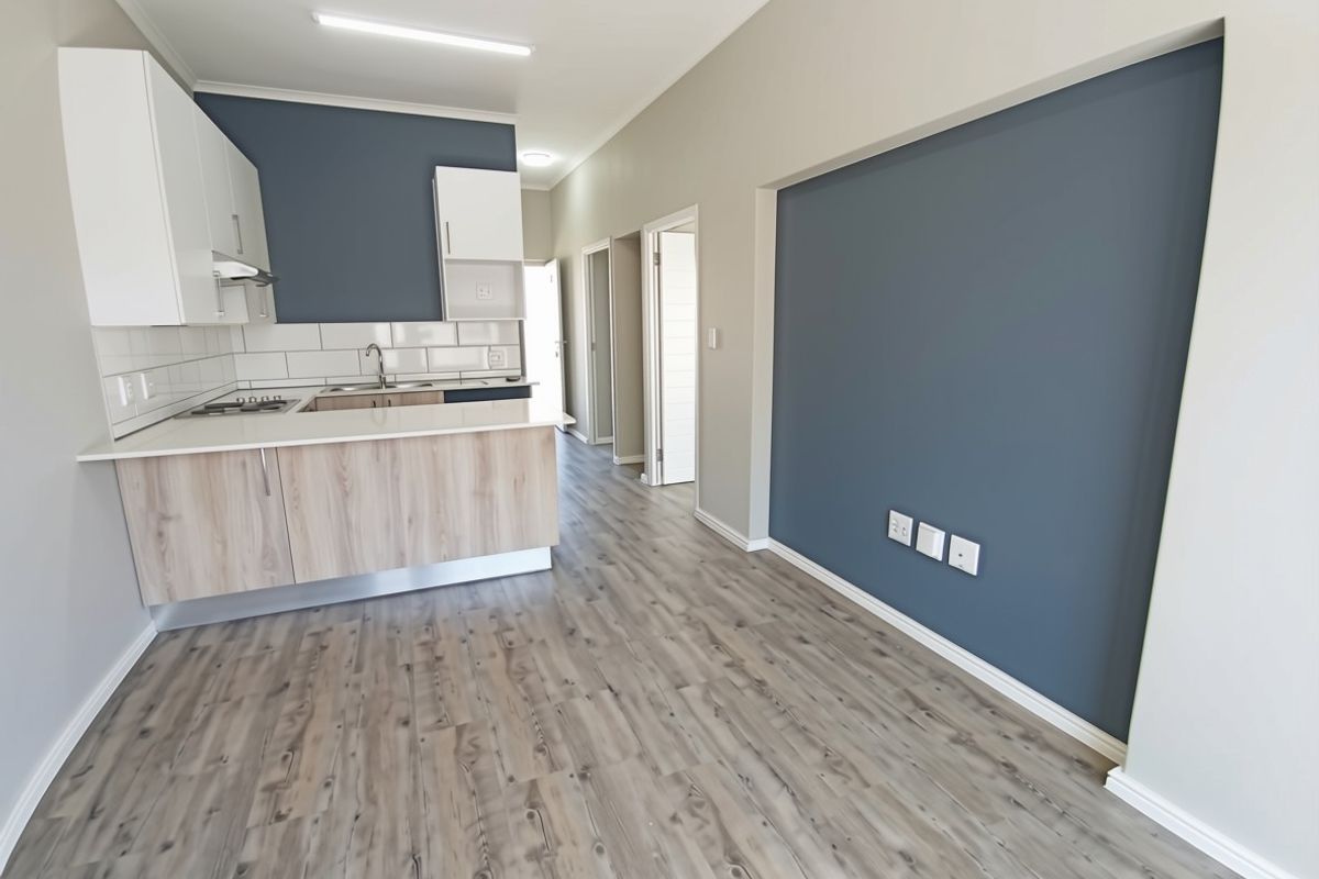 Modern open-plan living area featuring a contemporary kitchen with light wood cabinetry, stone countertops, and durable laminate flooring throughout the space.