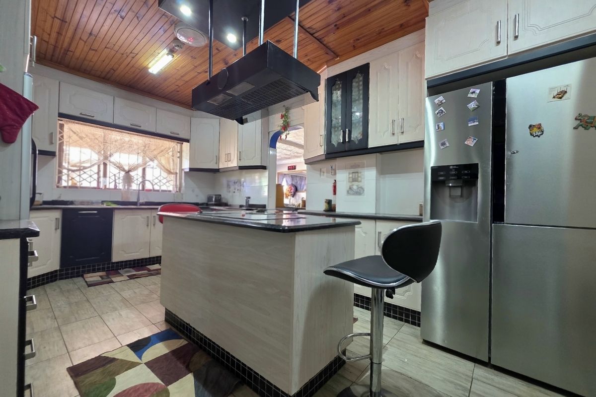A functional kitchen featuring a central island, built-in cabinetry, granite countertops, and a distinctive timber-paneled ceiling.