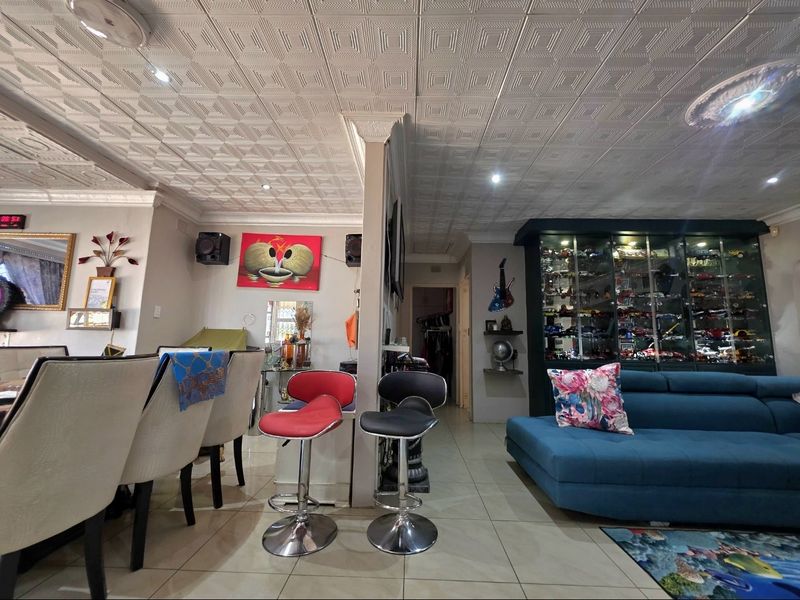 Open plan living and dining area featuring tiled flooring, decorative coffered ceilings with recessed lighting, and a large built-in display cabinet.