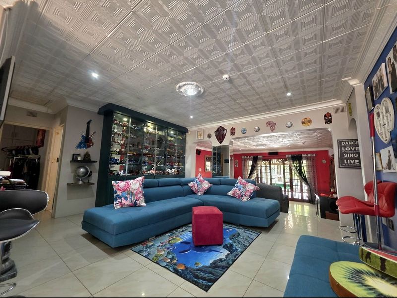 Spacious living area featuring tiled flooring, a decorative coffered ceiling, and built-in display cabinetry, offering a versatile space for relaxation and entertainment.