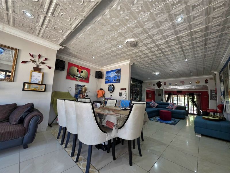 Spacious open-plan living and dining area featuring distinctive decorative pressed metal ceilings, tiled flooring, and recessed lighting with access to the rear.
