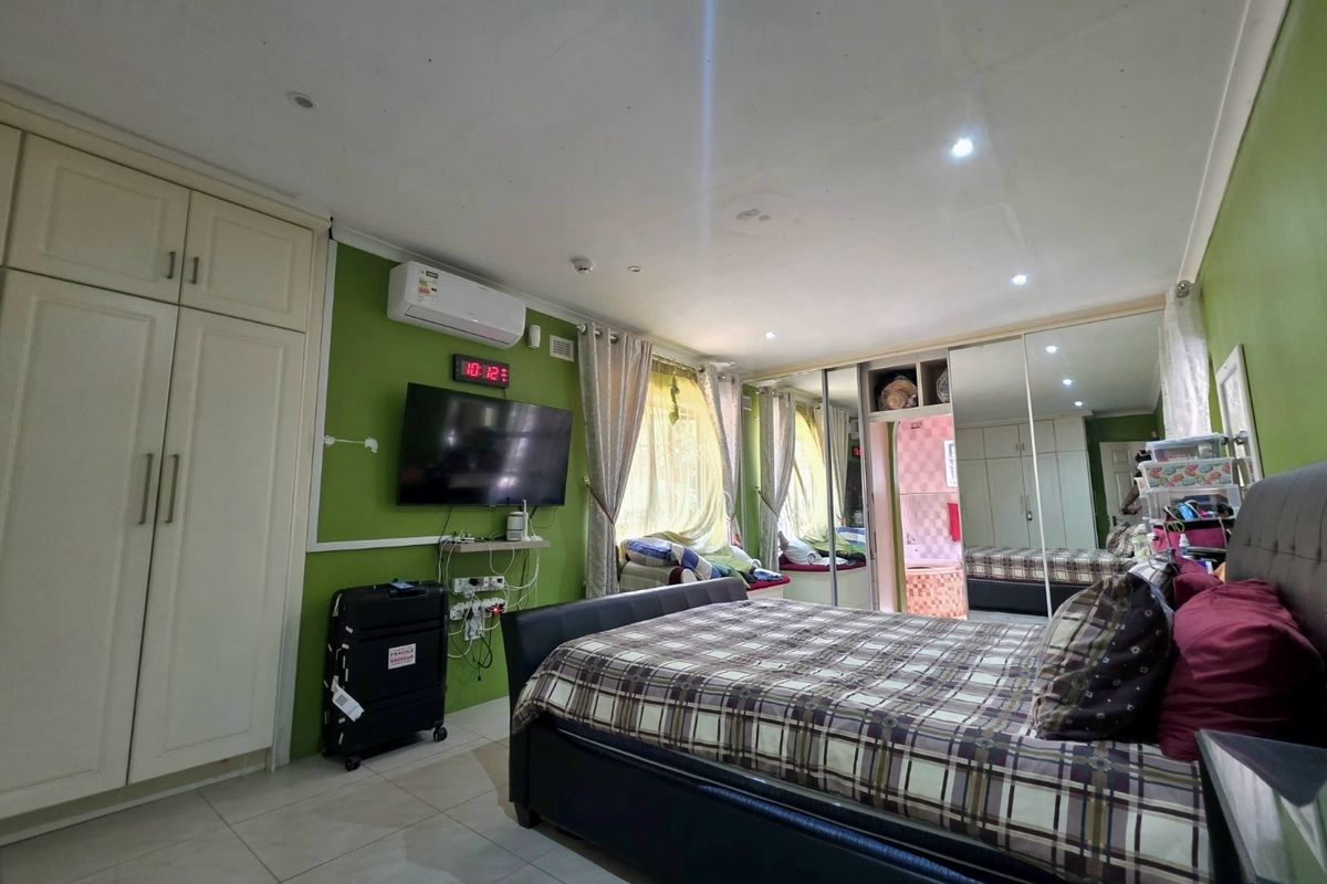 Spacious bedroom featuring built-in cupboards with mirrored doors, tiled flooring, recessed lighting, and a wall-mounted air conditioning unit.