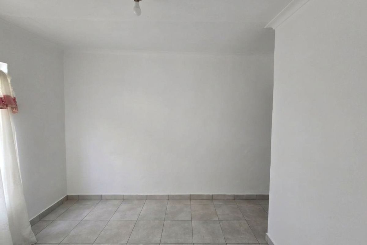 A clean, empty bedroom featuring neutral tiled flooring and simple white walls, providing a blank canvas for interior design.